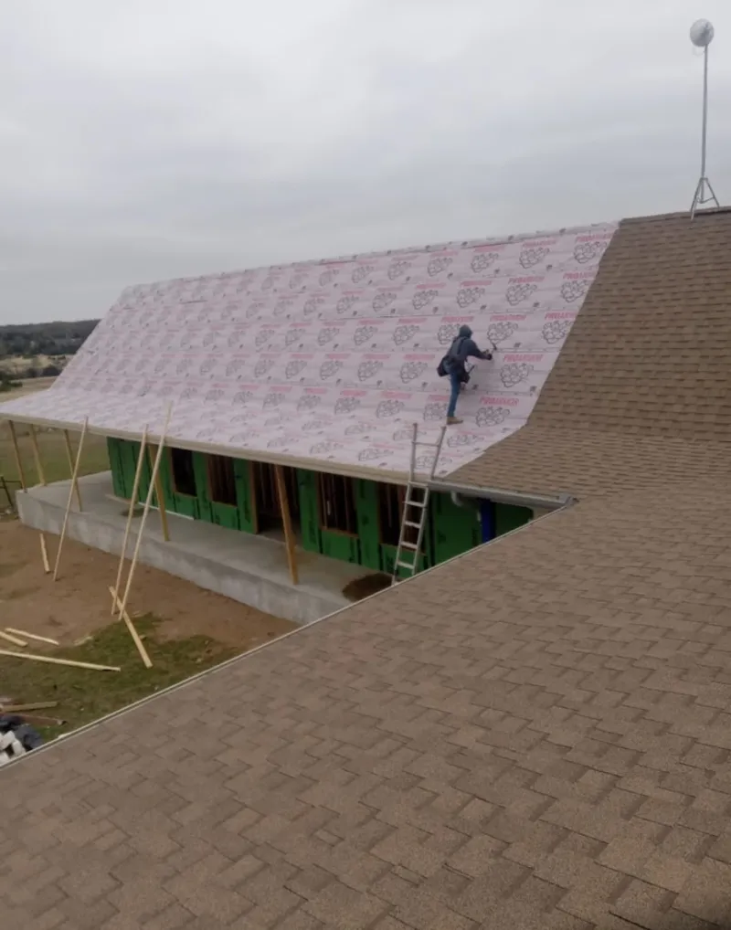 Worker preparing underlayment for a metal roof installation in Ogdensburg